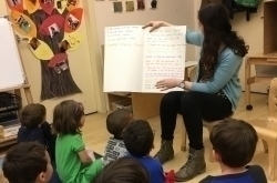 Anita showing big book to little kids in class room at YM&ແມ່ນແລ້ວ