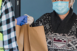 person handing over meal to a woman wearing mask at YM&ИӘ